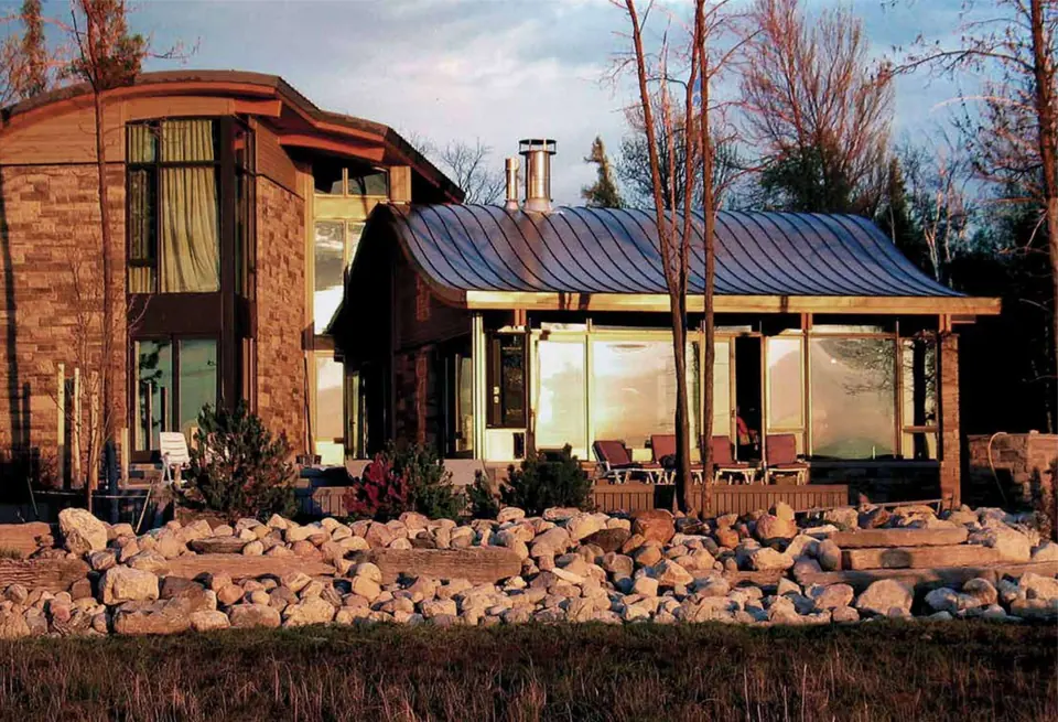 Lakeside cottage with a metal roof and stone landscaping