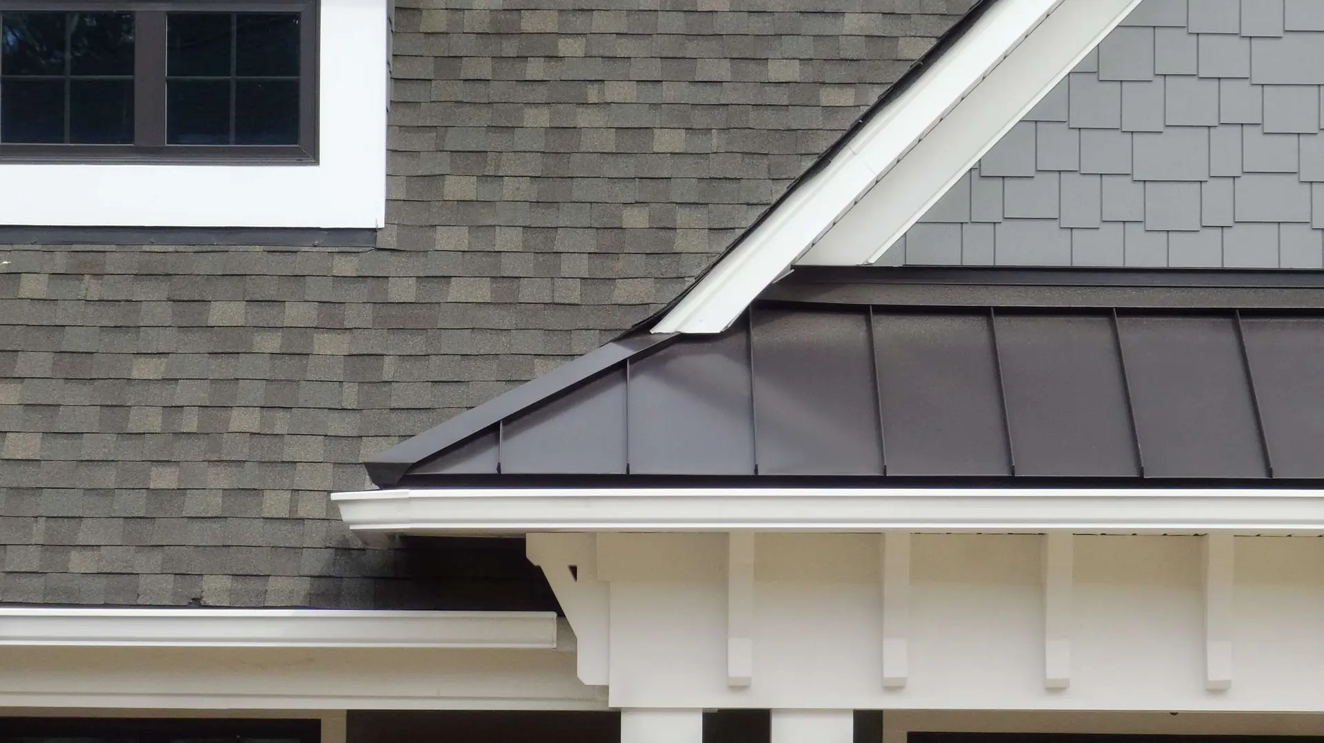 Standing-seam metal roof edge on a home with shingle siding