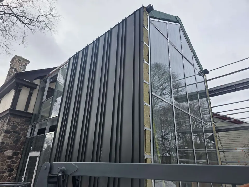 Black standing-seam cladding meeting tall windows