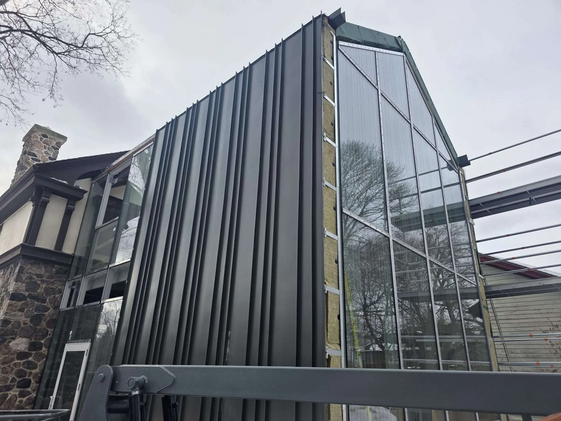Black standing-seam metal cladding wrapping a modern home with tall glazing